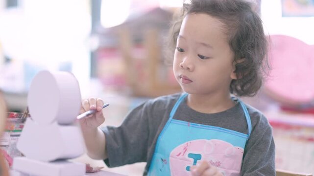 Young child learning painting while decorating a plaster figurine with a brush, developing artistic skills, creativity, concentration, imagination.