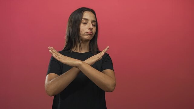 Young hispanic woman arms crossed x with pouting lips and closed eyes in pink studio; rejection assertiveness boundary.