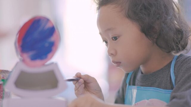 Young child learning painting while decorating a plaster figurine with a brush, developing artistic skills, creativity, concentration, imagination.
