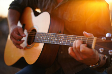 Fototapeta premium Jazz Day Person playing acoustic guitar with warm sunset light flare music