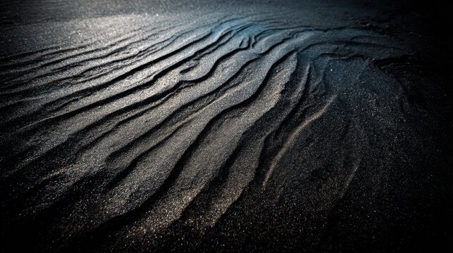 Wind-sculpted dark sand ripples creating rhythmic wave patterns on a textured shoreline