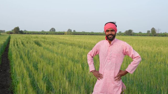 Young indian farmer standing at wheat agriculture field	