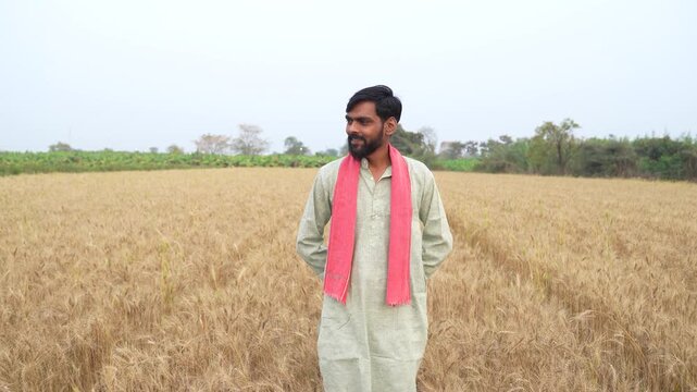 Young Indian farmer standing at wheat agriculture field 