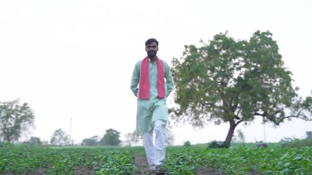 Young indian farmer standing at wheat agriculture field