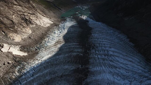 Glacier tongue with deep blue ice patterns and lateral moraine flowing down Norwegian mountain valley