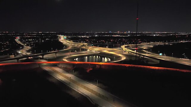 An aerial view of a large stack interchange on Florida's Turnpike on a clear night. The camera dolly in, boom up and tilt down over the intersection and retention ponds in the landscape.