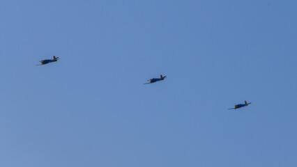 Fototapeta premium Three propeller aircraft flying in formation against a bright clear sky during an aerial aviation display