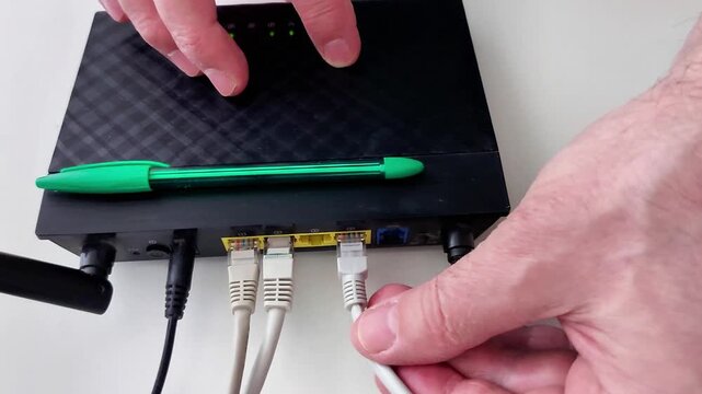 Hands interacting with a router while connection a cable, showing network setup, troubleshooting, and connectivity management for reliable home or office internet access