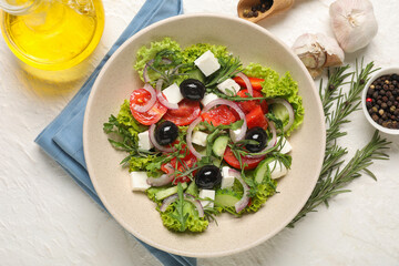 Bowl with tasty Greek salad, spices and oil on light background