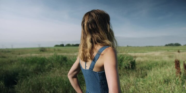 Young woman standing in a wild grass meadow