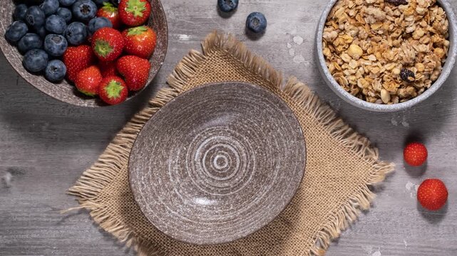 Stop motion animation of yogurt with granola and berries. Eating Greek yogurt with crunchy oat granola with honey, blueberries, and strawberries. Healthy food, healthy breakfast concept