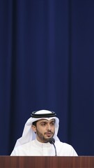 Arab businessman in traditional kandura giving a formal speech at a conference podium for corporate communication