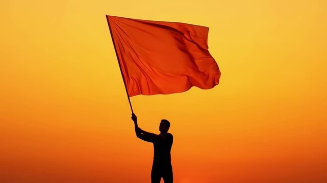 Silhouette of a Person Holding a Large Saffron Flag During Sunset with Vibrant Sky Background