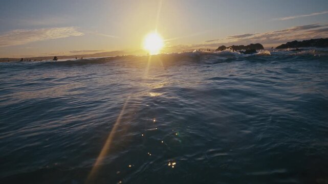 Low sun glows by breaking wave as surface water surges toward the camera
