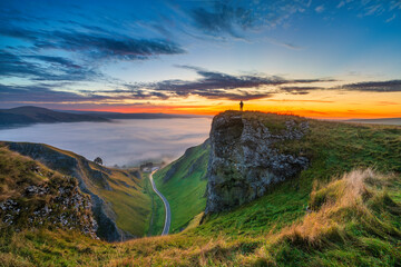 Solo traveller watching sunrise with cloud inversion at hope valley near Winnats Pass in Peak District. England 