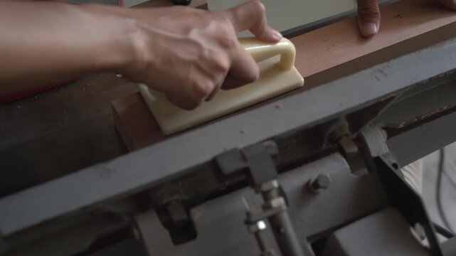 carpenter using push block to plane wood on jointer machine