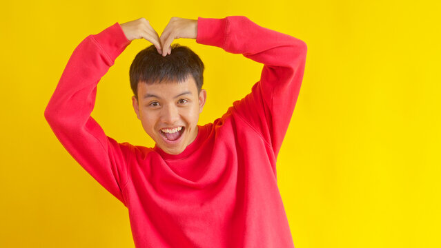 Energetic Young Guy Expressing Love with Arms Raised in Heart Symbol