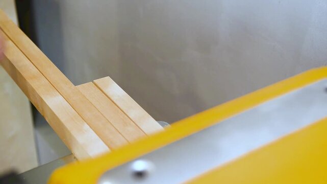 Carpenter shaping wooden block on planer thicknesser jointer machine in workshop.
