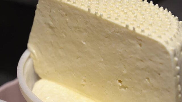 Freshly molded cheese block draining liquid from its bottom portion