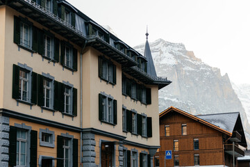 Scenic alpine village with traditional houses and green pastures set against dramatic mountains and rocky cliffs in a peaceful rural landscape. © Христя Сидор
