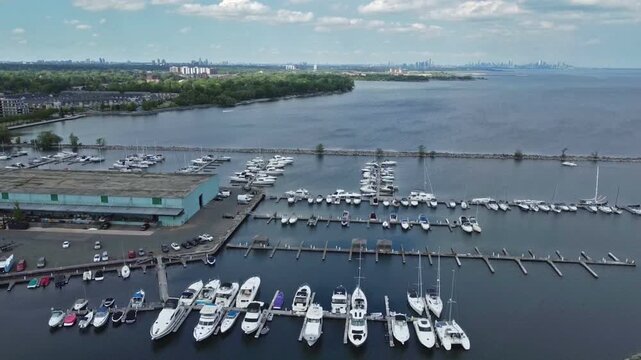 The harbour in Port Credit, Mississauga, Ontario, Canada. Aerial drone shot tilting down during a warm summer afternoon looking east towards Toronto, visible in the distance.