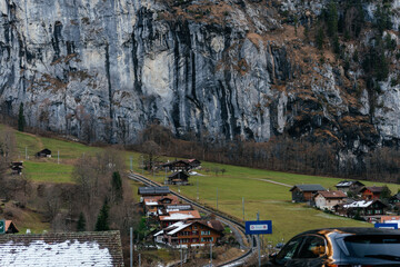 Scenic alpine village with traditional houses and green pastures set against dramatic mountains and rocky cliffs in a peaceful rural landscape. © Христя Сидор