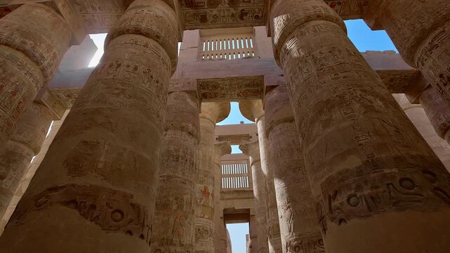 Karnak Temple in Luxor, Egypt. Massive hieroglyphic columns in Great Hypostyle Hall, Karnak Temple Luxor Egypt. Upward view of ancient carved pillars against blue sky.