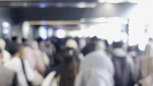 Motion-blurred commuters moving toward the exit gate inside a busy railway station. The footage represents rush hour commuting, public transportation flow, and the fast pace of urban life.