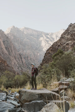 Female hiker hiking w camera in deep valley of Hajar Mountains, Oman