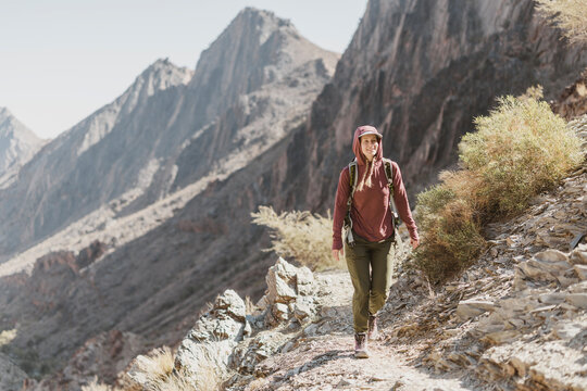 Woman hikes along trail in dramatic Hajar Mountains, Oman