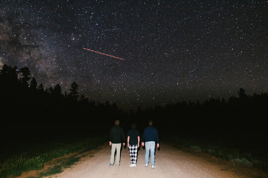 Teenage boys together on road under starry sky at night