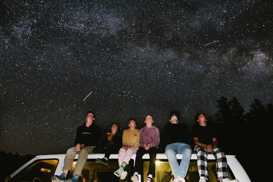Cousins together on top of a car looking at Milky Way and star sky