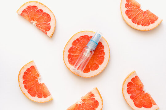 slices of grapefruit. A bottle of perfume against a background of grapefruits. Grapefruits and an empty bottle. Grapefruit perfume.