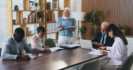Woman, tablet and discussion with team in office meeting on app with review, insight or talk at...