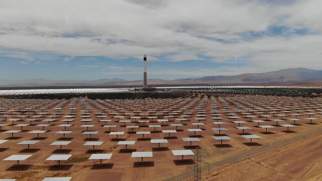 Aerial view of heliostat mirrors surrounding the solar tower at Noor concentrated solar power plant in Ouarzazate Morocco highlighting renewable energy technology in the desert.