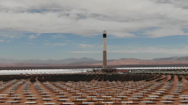 Aerial view of the solar power tower at Noor concentrated solar power plant in Ouarzazate Morocco surrounded by heliostat mirrors in the desert landscape.