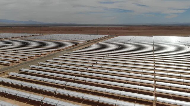 Aerial view of parabolic trough solar collectors at Noor solar power complex in Ouarzazate Morocco highlighting large scale renewable energy infrastructure in the desert.