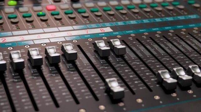 Professional Digital Audio Mixing Console in Studio. Close-up of a audio mixer with faders and backlit buttons. Professional sound equipment for recording studios, live concerts, and broadcasting.