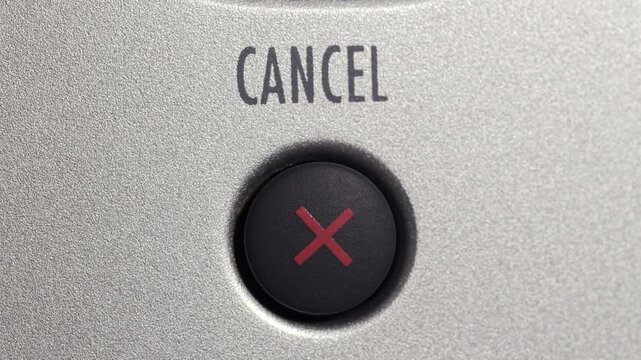 Close up of finger pressing cancel button on silver control panel