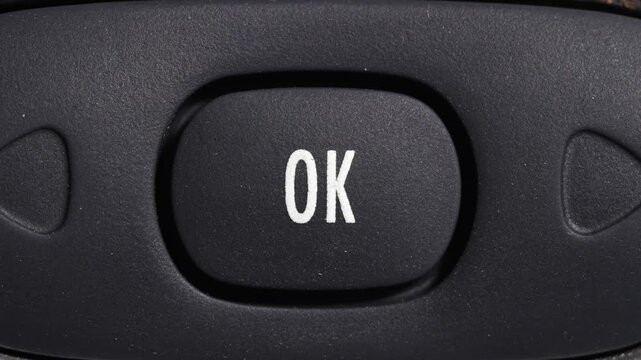 Close up of finger pressing OK button on dark control panel