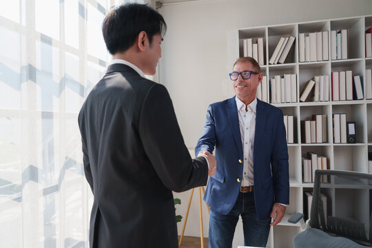 Businessmen shaking hands sealing partnership agreement in office