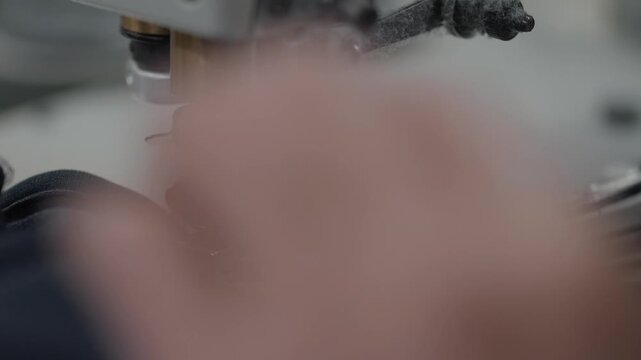 Industrial collarette sewing machine feeding elastic band while operator guides fabric during garment production