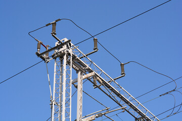 A complex steel lattice structure supports high voltage overhead power lines for a railway system...