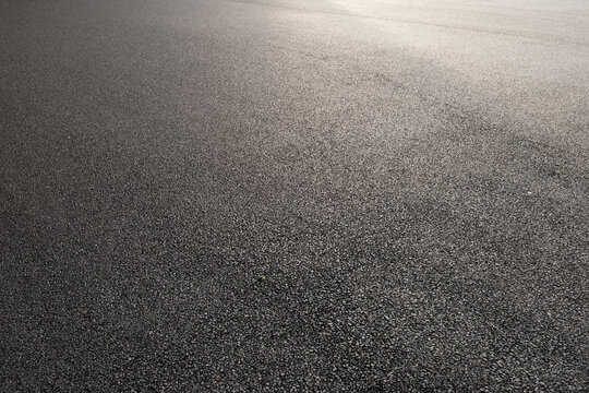 High angle view of gray asphalt road surface texture with sunlight reflection