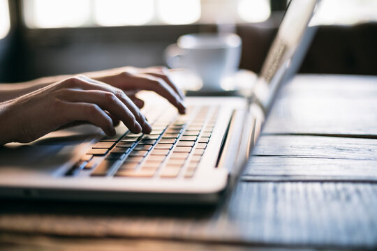 Cropped image of woman hand using laptop in cafe