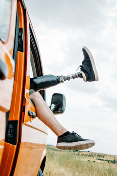 Legs of prosthetic young man dangling out of camper van window