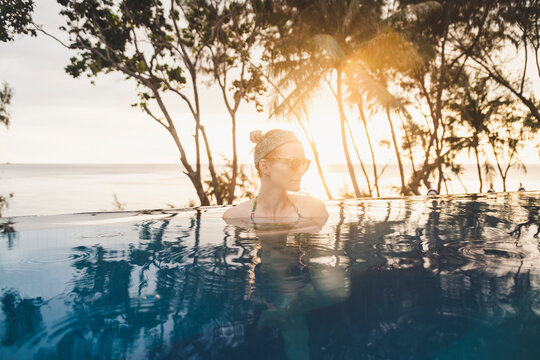 Woman in infinity pool at sunset, Nai Thon Beach, Phuket, Thailand