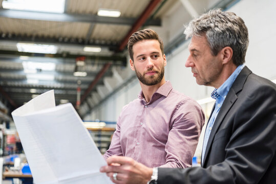 Businessmen with plan during meeting in production hall