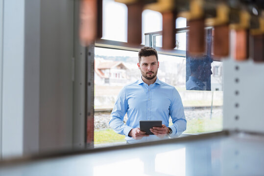 Businessman with tablet in company looking at product