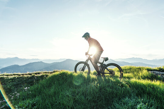 Mountainbiker against the sun on a way in Grisons, Switzerland